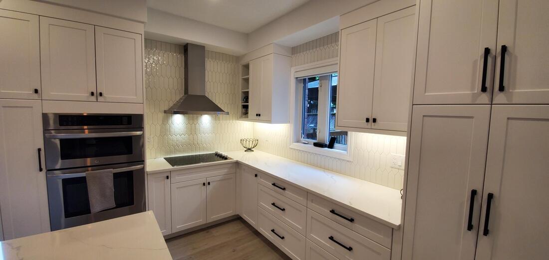 Built-in oven and microwave. Stainless steel hoodvent. Picket fence tile backsplash. Quartz countertop.