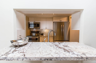 Granite form breakfast bar, white shaker cabinets in condo kitchen.