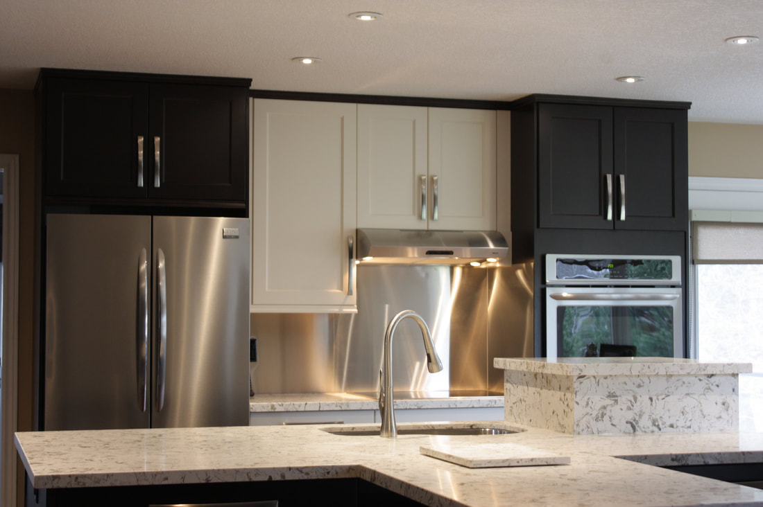 Picture. Stainlees Steel backsplash two tone kitchen with shaker doors. Stainless steel appliances. Quartz countertop